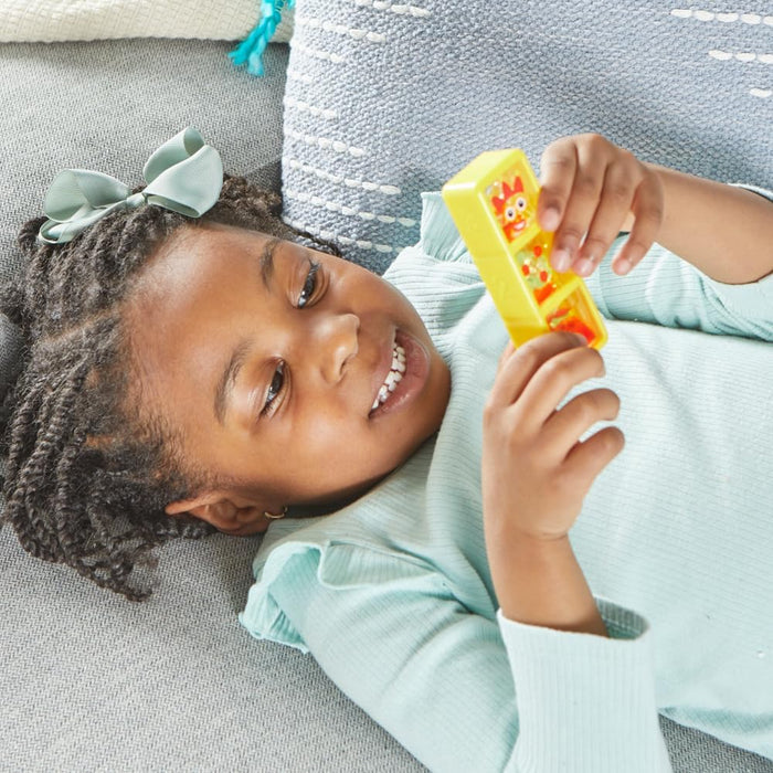 Young girl lying down, playing with a yellow rectangular sensory bottle featuring Numberblocks character faces.