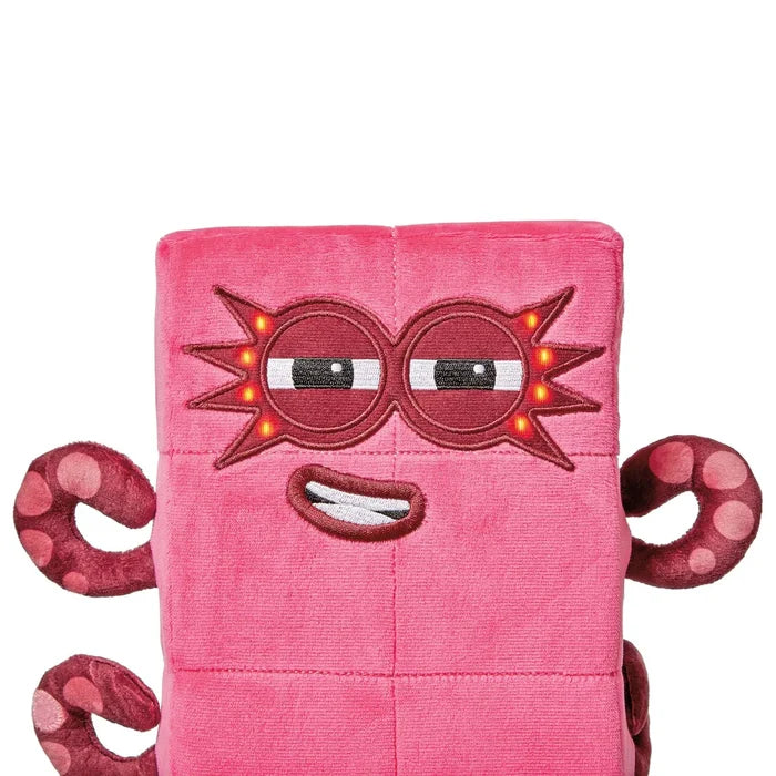 Pink block-shaped plush toy with light-up star glasses, an embroidered smirk, and curly tentacles.