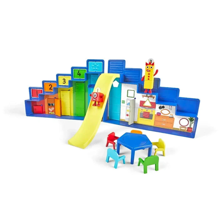 Blue stepped playset with yellow slide, numbered lockers, two block figures, and a blue table with colorful chairs.