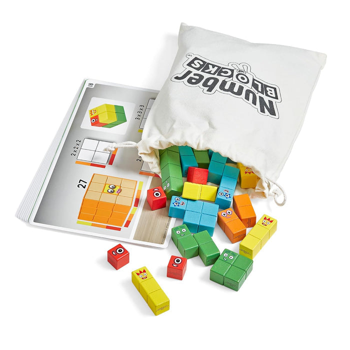 Colorful wooden character blocks with faces spilling from a white bag next to a math and building activity book.