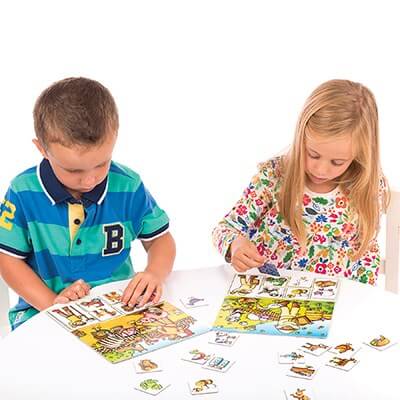 Two children playing a colorful farm-themed matching game with illustrated boards and small square animal cards.