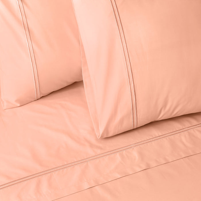 Organic cotton coloured sheet set in peach nectar with embroidery, 250 thread count from Whites of London NZ.