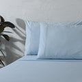 Organic cotton coloured sheet set in sky blue, 250 thread count, from Whites of London NZ, displayed on a bed.