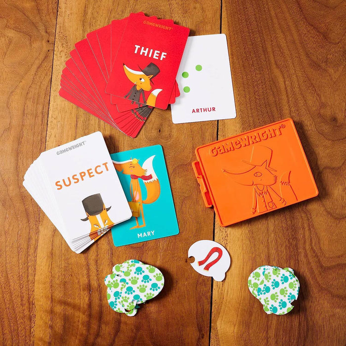 Red and white fox-themed playing cards, character tokens, and an orange plastic case on a wooden tabletop.