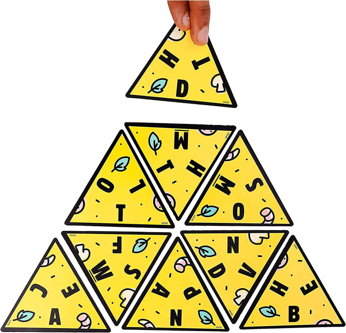 Hand placing a yellow triangular tile onto a pyramid of game pieces with black letters and food illustrations.