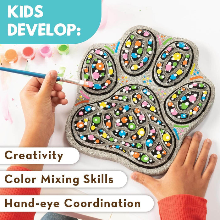 Child painting colorful dots on a grey paw print stepping stone with paint pots and developmental skill text visible.