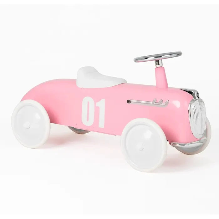 Pale pink vintage-style ride-on roadster with white wheels, white seat, chrome steering wheel, and number 01 on the side.