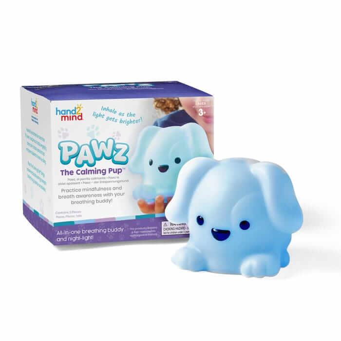 Smiling light blue puppy nightlight glowing next to its white and purple PAWZ The Calming Pup product box.