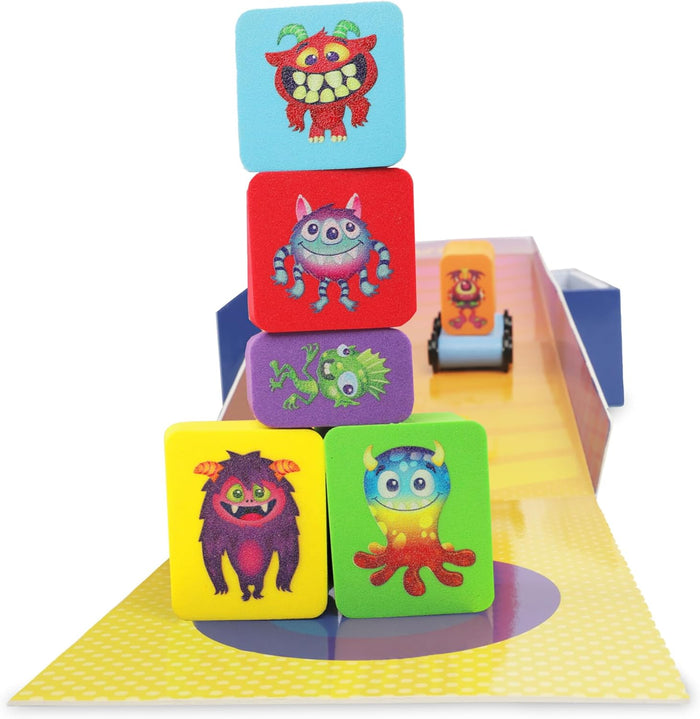 Five colorful foam blocks with monster illustrations stacked in a tower with a wheeled block car in the background.