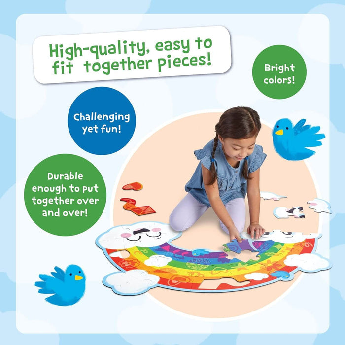 Child assembling a large, colorful rainbow-shaped floor puzzle featuring smiling cloud pieces and blue bird graphics.