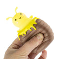 Hand squeezing a brown beehive squishy; a smiling yellow bee with honey drips pops out of the top.