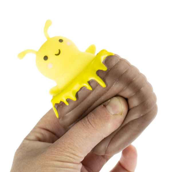 Hand squeezing a brown beehive squishy; a smiling yellow bee with honey drips pops out of the top.