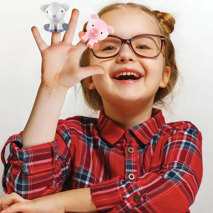 Smiling girl in glasses and a red plaid shirt wears a white sheep and pink pig finger puppet on her hand.