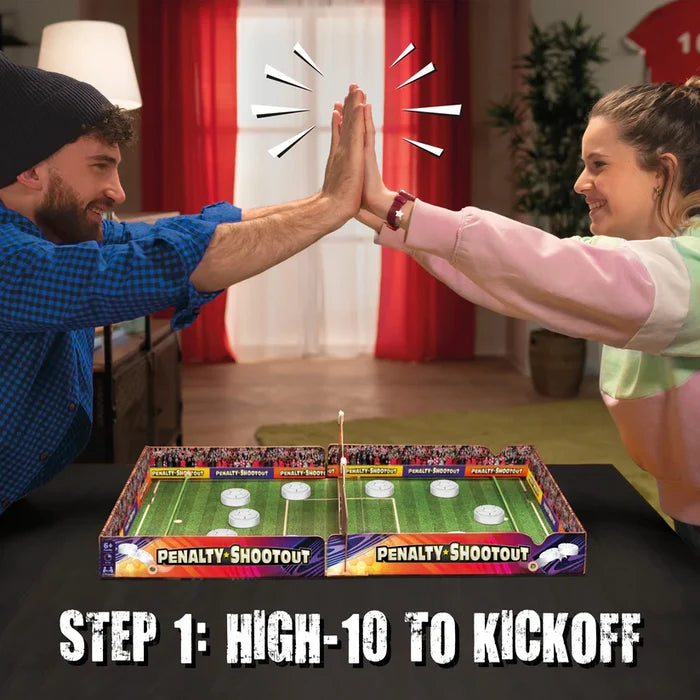 Two people high-ten over a Penalty Shootout tabletop soccer game featuring a green pitch and white sliding pucks.