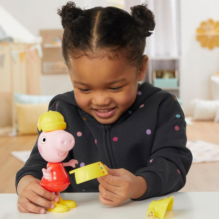 A child plays with a Peppa Pig figure in a red dress, attaching a yellow snap-on outfit piece.
