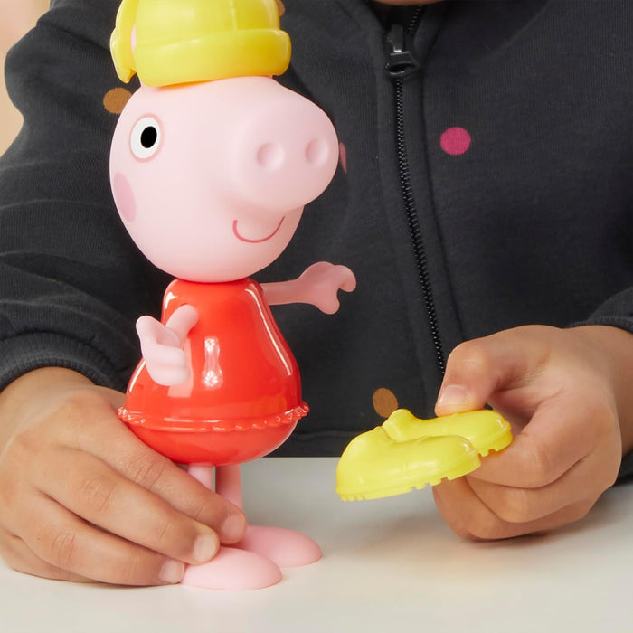 Child holding a Peppa Pig figure in a red dress and yellow hat with a yellow boot accessory.