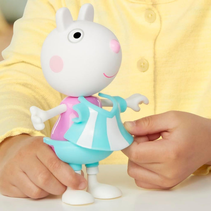 Child's hands dressing a Suzy Sheep toy in a blue and white striped clip-on dress.