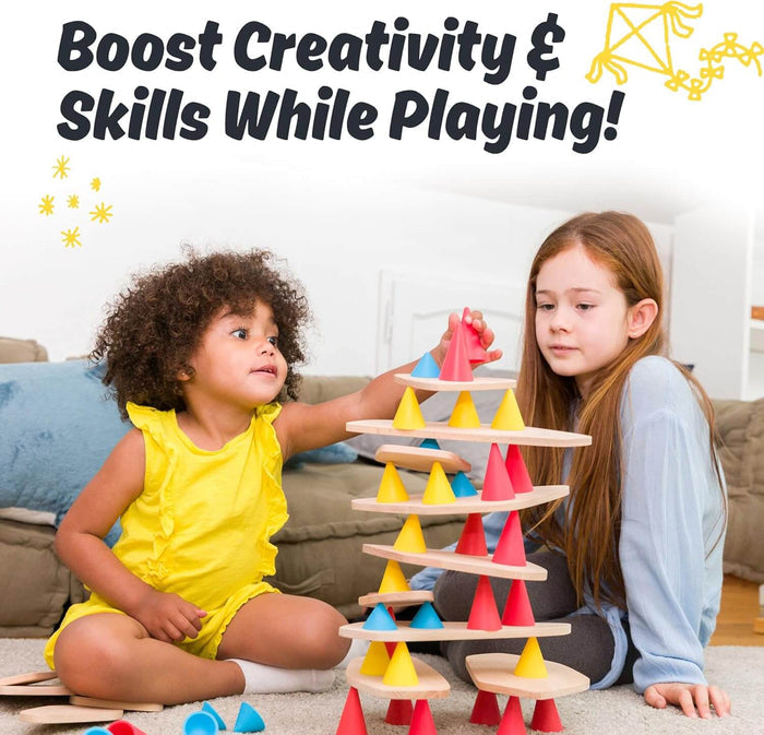Two girls build a balancing tower using light wooden planks and colorful red, yellow, and blue silicone cones.