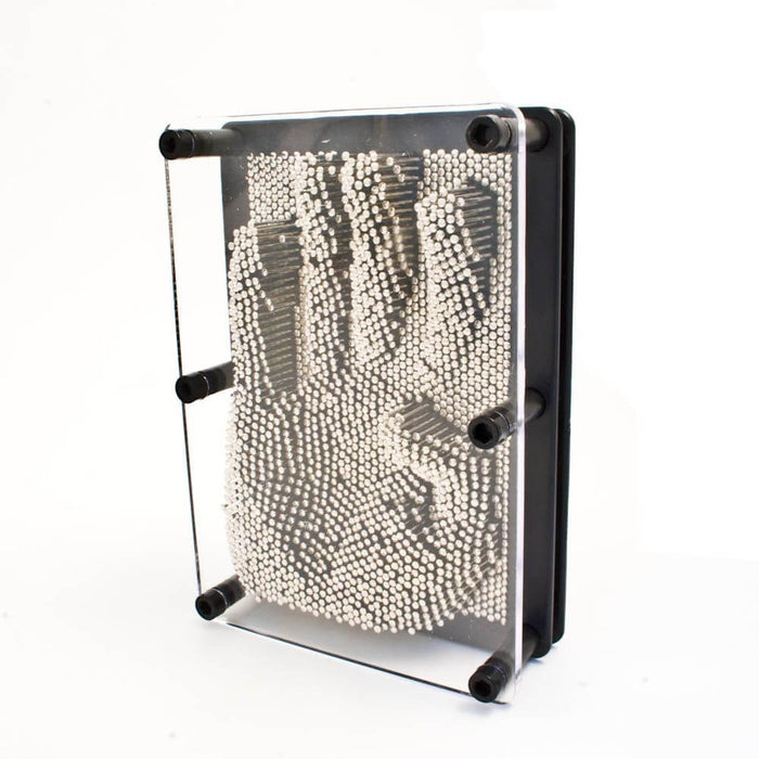 Rectangular toy with silver metal pins in a black frame showing a 3D hand impression behind clear plastic.