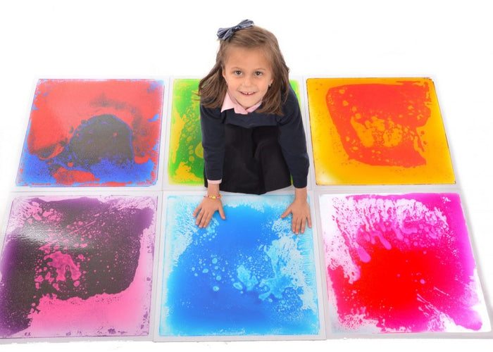 Girl sitting on a 3x2 grid of six colorful, 50cm square liquid floor tiles with swirling marbled patterns.