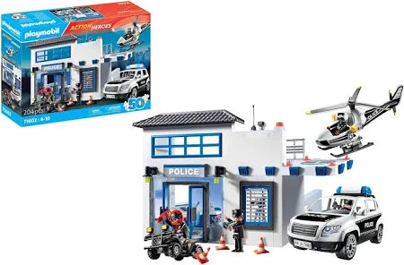 Playmobil toy police station set including a white building, helicopter, police SUV, quad bike, figures, and box.