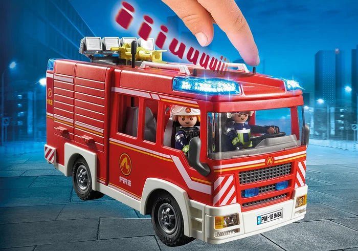 Red toy fire truck with flashing blue lights and two figures. A hand presses a sound button on the roof.