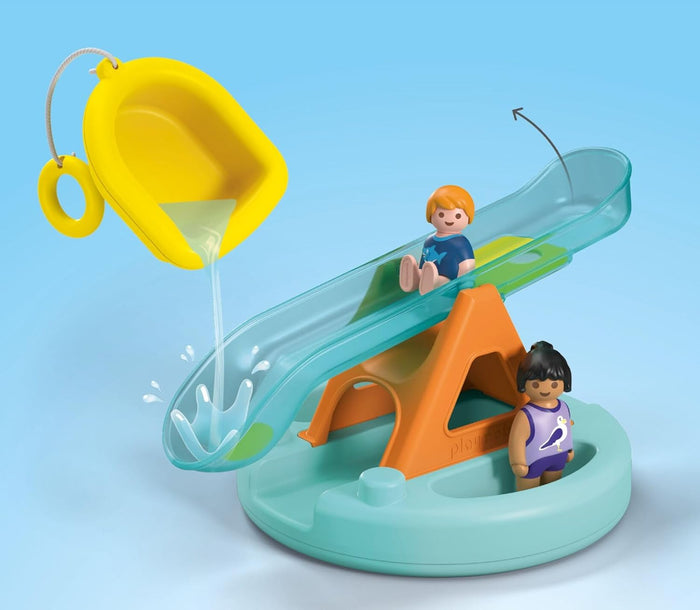Water pouring from a yellow scoop into a turquoise seesaw slide with two toy figures on a blue and orange base.