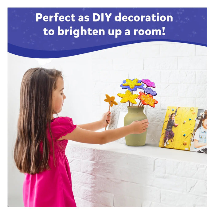 Girl placing sparkly, star-shaped DIY craft flowers into a green vase on a white brick mantel.