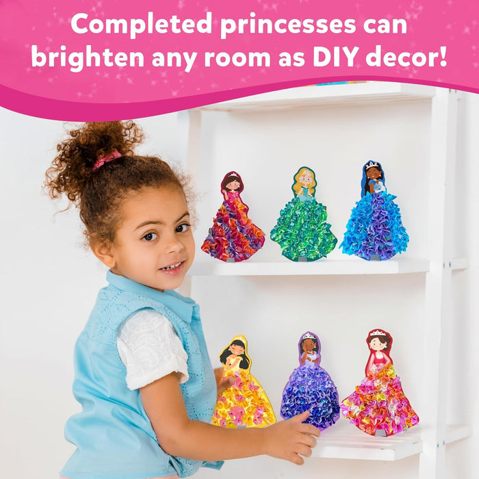 Young girl with six finished princess crafts featuring colorful, 3D textured tissue paper dresses on a white shelf.
