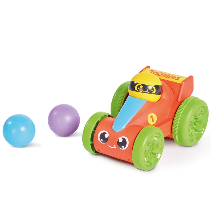 Red toy race car with green wheels and a yellow driver, pictured alongside a blue and a purple ball.