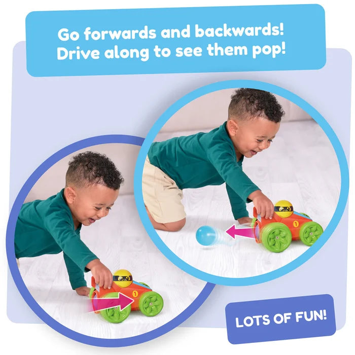 Toddler playing with a red toy car with green wheels and yellow driver that pops out blue balls as it moves.