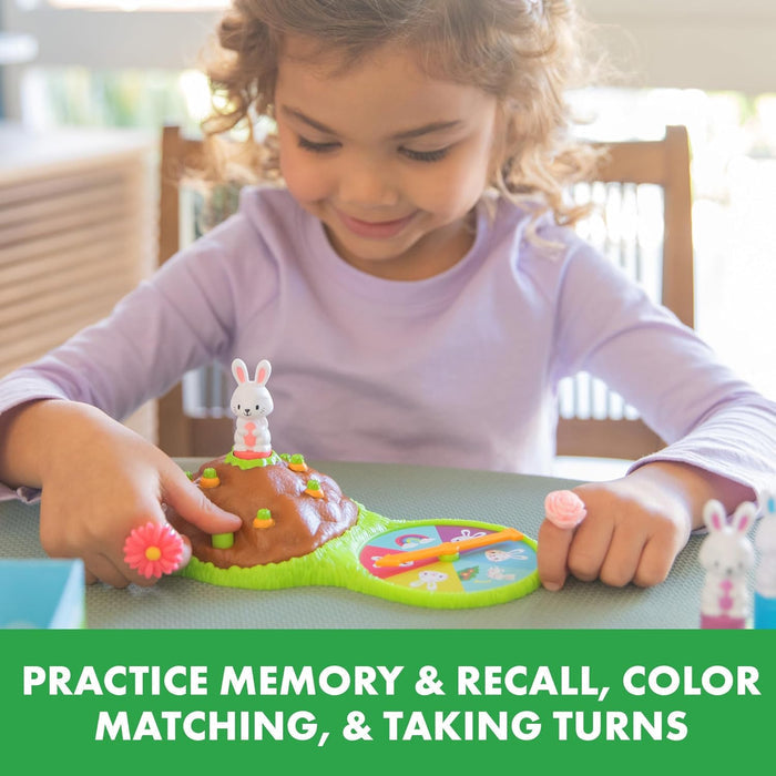 Child playing with a bunny-themed board game featuring white rabbits, a brown mound, and a colorful spinner.