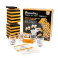 Orange and black wooden block tower with shot glasses and punishment cards in front of a vibrant orange game box.