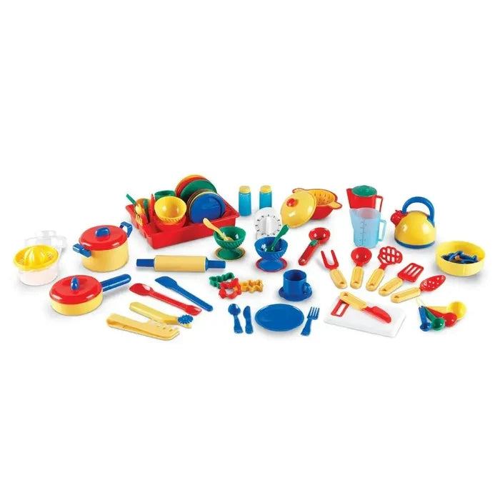 Collection of colorful red, yellow, blue, and green plastic toy pots, pans, dishes, and utensils on white.