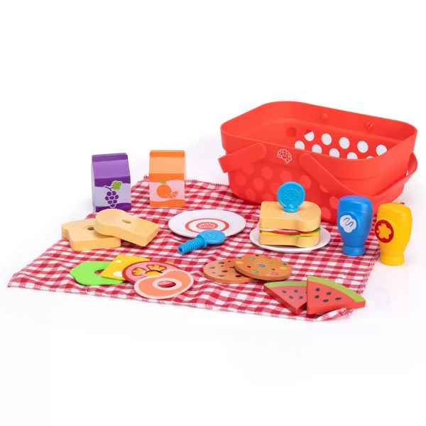 Red toy picnic basket on a checkered cloth with wooden play food like sandwiches, fruit, and juice boxes.