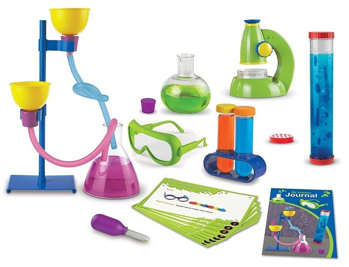 Colorful toy science kit featuring a green microscope, flasks, test tubes, safety goggles, and activity cards.