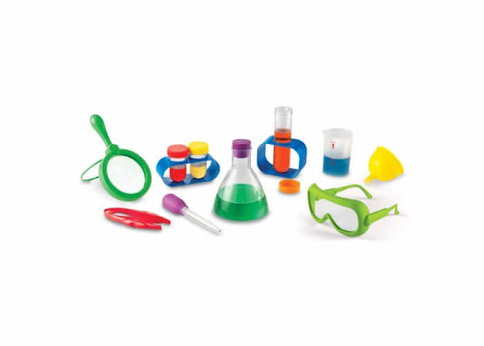Colorful toy science equipment: magnifying glass, green flask, test tubes, beaker, and lime green safety goggles.