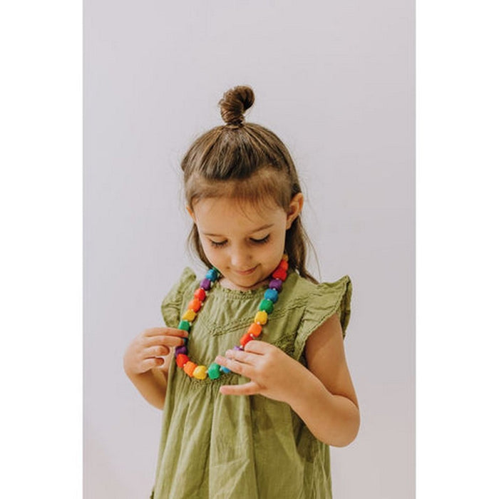 A young girl wearing a necklace with large, chunky faceted beads in bright rainbow colors.