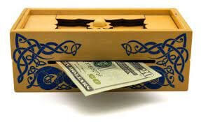 Yellow wooden puzzle box with blue Celtic knot patterns and a twenty-dollar bill sticking out of a front slot.