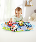 Baby playing with soft red, yellow, blue, and white toy cars on a colorful city road map play mat.