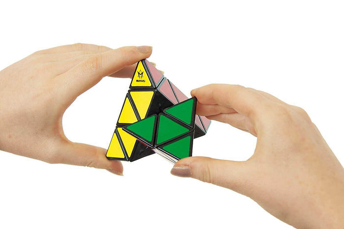 Hands twisting a triangular Pyraminx puzzle with yellow, green, and pink faces on a black frame.