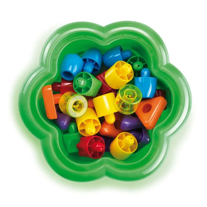 Colorful, chunky plastic pegs in various shapes stored inside a green flower-shaped container.
