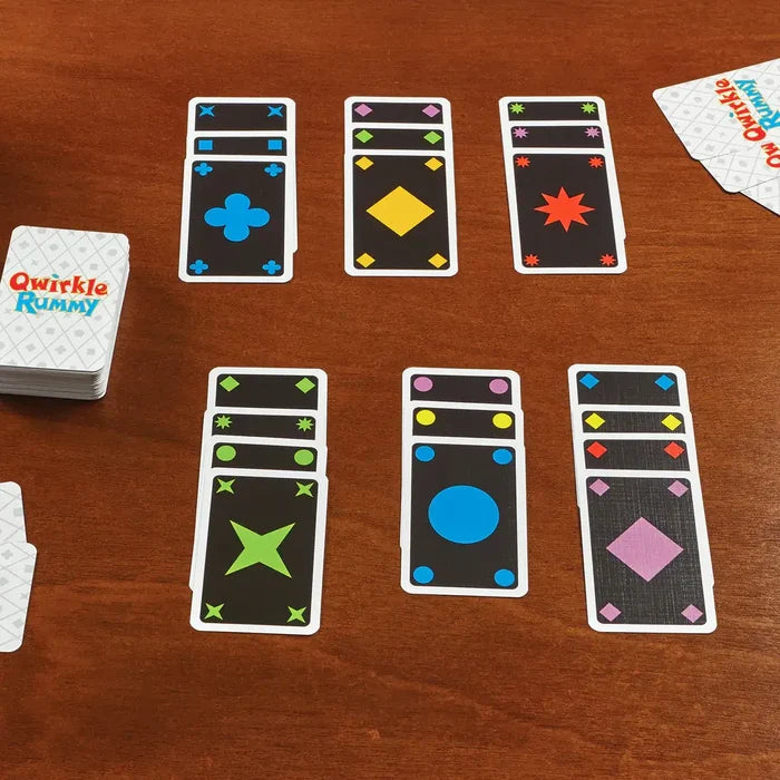 Qwirkle Rummy cards on a wooden table showing sets of colorful shapes with small icons at the top for accessibility.