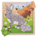 16-piece wooden puzzle of a large and small grey rabbit in a grassy meadow. Two puzzle pieces are set aside.