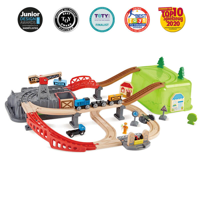 Colorful multi-level wooden train set with red bridges, a crane, blue engine, and a green storage bucket hill.