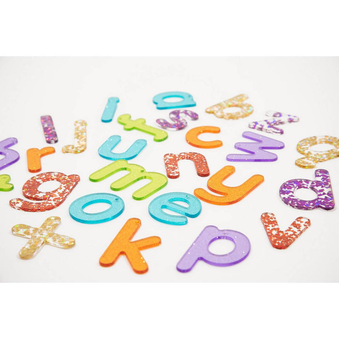 Colorful, translucent glitter lowercase letters scattered on a white background.