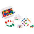 Colorful smooth pebbles in a clear storage bin with activity cards and stone patterns arranged on a white surface.