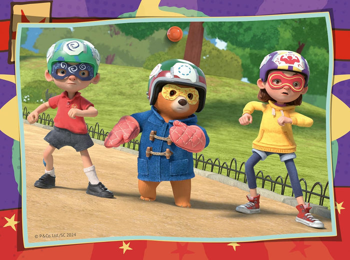 Paddington Bear and two children in colorful superhero helmets and masks posing in a sunny park.