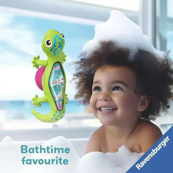 Green suction gecko toy with colorful rainmaker beads shown next to a smiling toddler in a bubble bath.