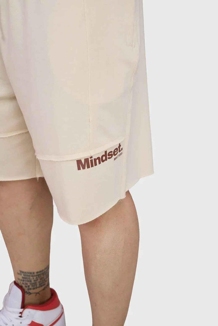 Beige raw edge oversized shorts by Fuaark Nz, featuring a relaxed fit and casual style, shown on a model.